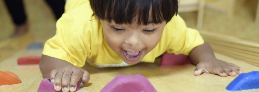 Menino com síndrome de Down brinca em estrutura de escalada no Crei Sesc Senac, espaço voltado para inclusão e autonomia de pessoas com deficiência.
